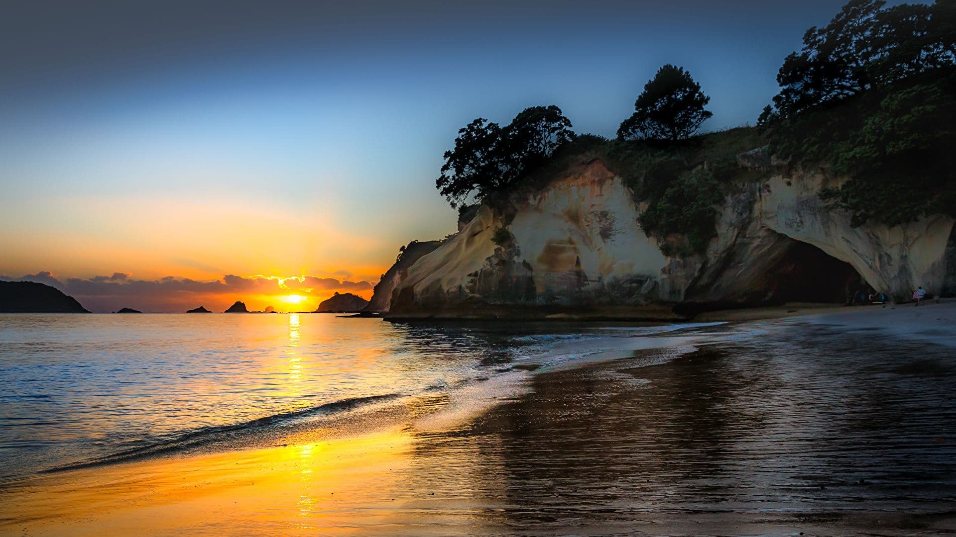 Sunrise over a beach, with cliffs in the midground.