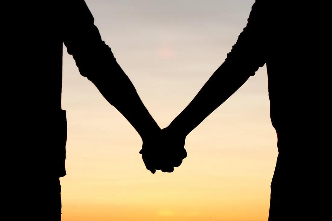 silhouette of two people holding hands